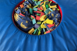 rundes blaues Bauelement gefüllt mit Kleinspielteilen in einer Turnhalle